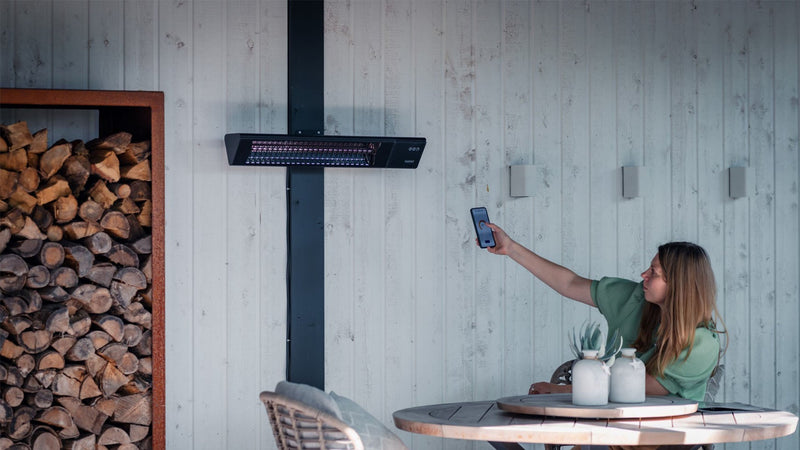 Zwarte Sunred Triangle Dark SMART wandmodel heater op afstand bestuurbaar in gezellige tuin

